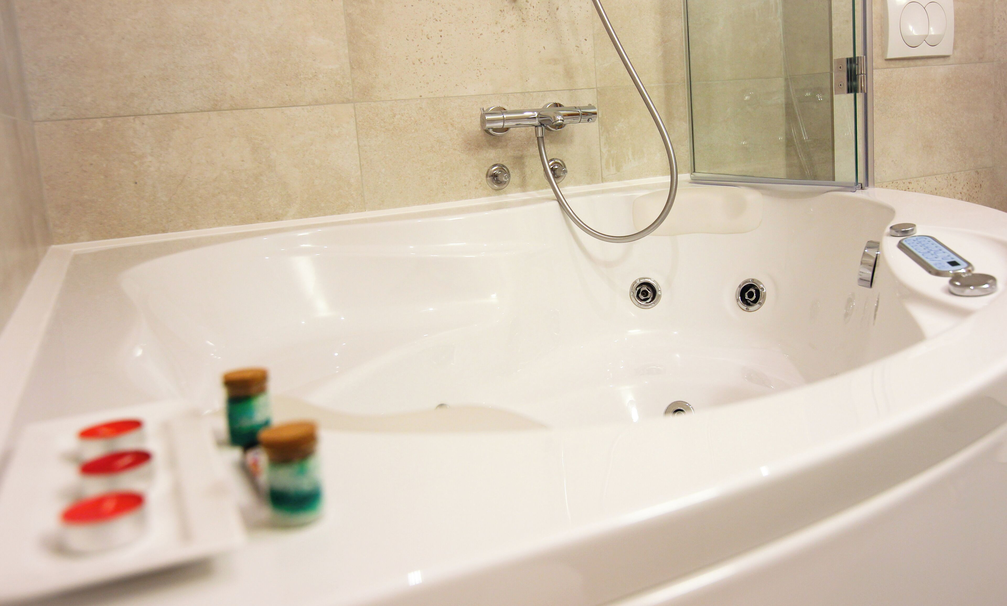 Una bañera grande y blanca con ducha de mano, asiento integrado y panel de control.