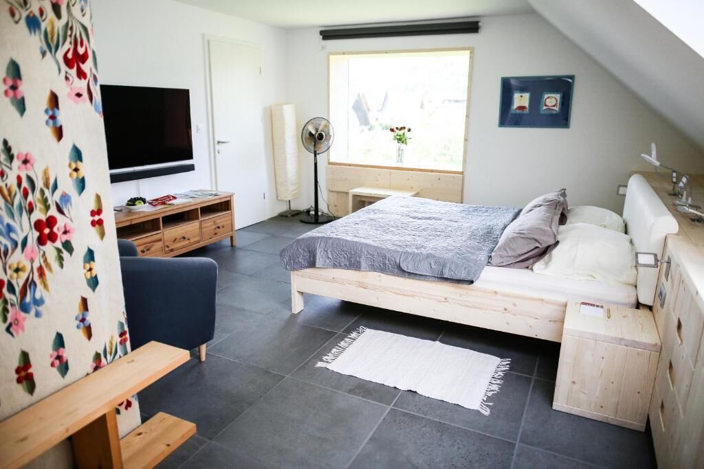 A bedroom with a bed, a TV, a desk, and a window.
