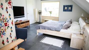 A bedroom with a bed, a TV, a desk, and a window.