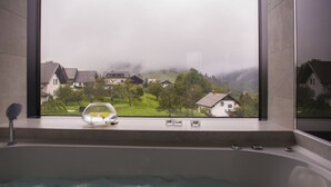 A bathtub with a view of a residential area through a window. - eco boutique hotel A.M.S. Beagle Bled (Gorje)
