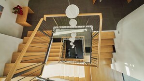A modern interior with a wooden staircase, a central light fixture, and a small table with a potted plant. - eco boutique hotel A.M.S. Beagle Bled (Gorje)