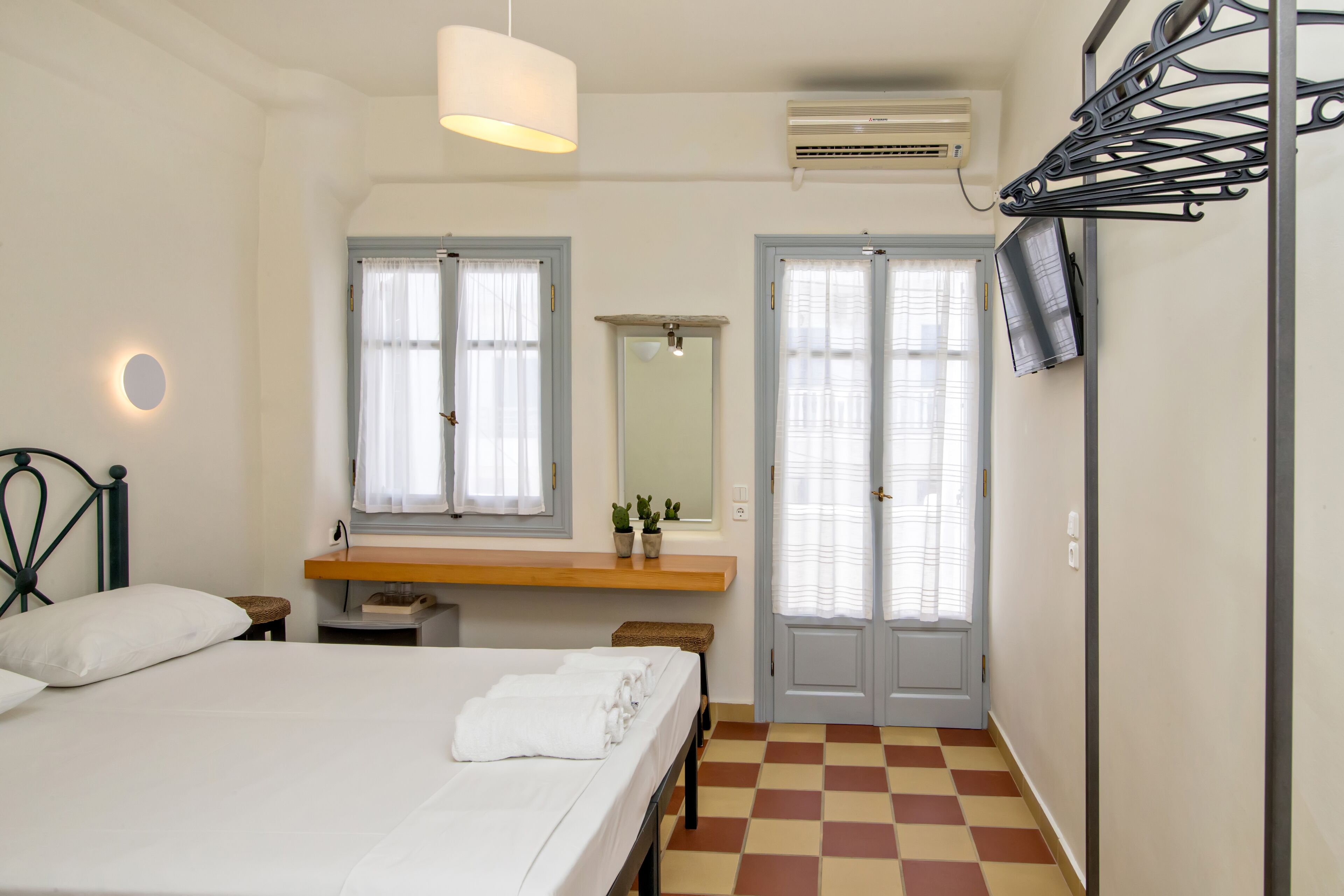 A bedroom with a bed, bedside table, mirror, and a checkered floor.