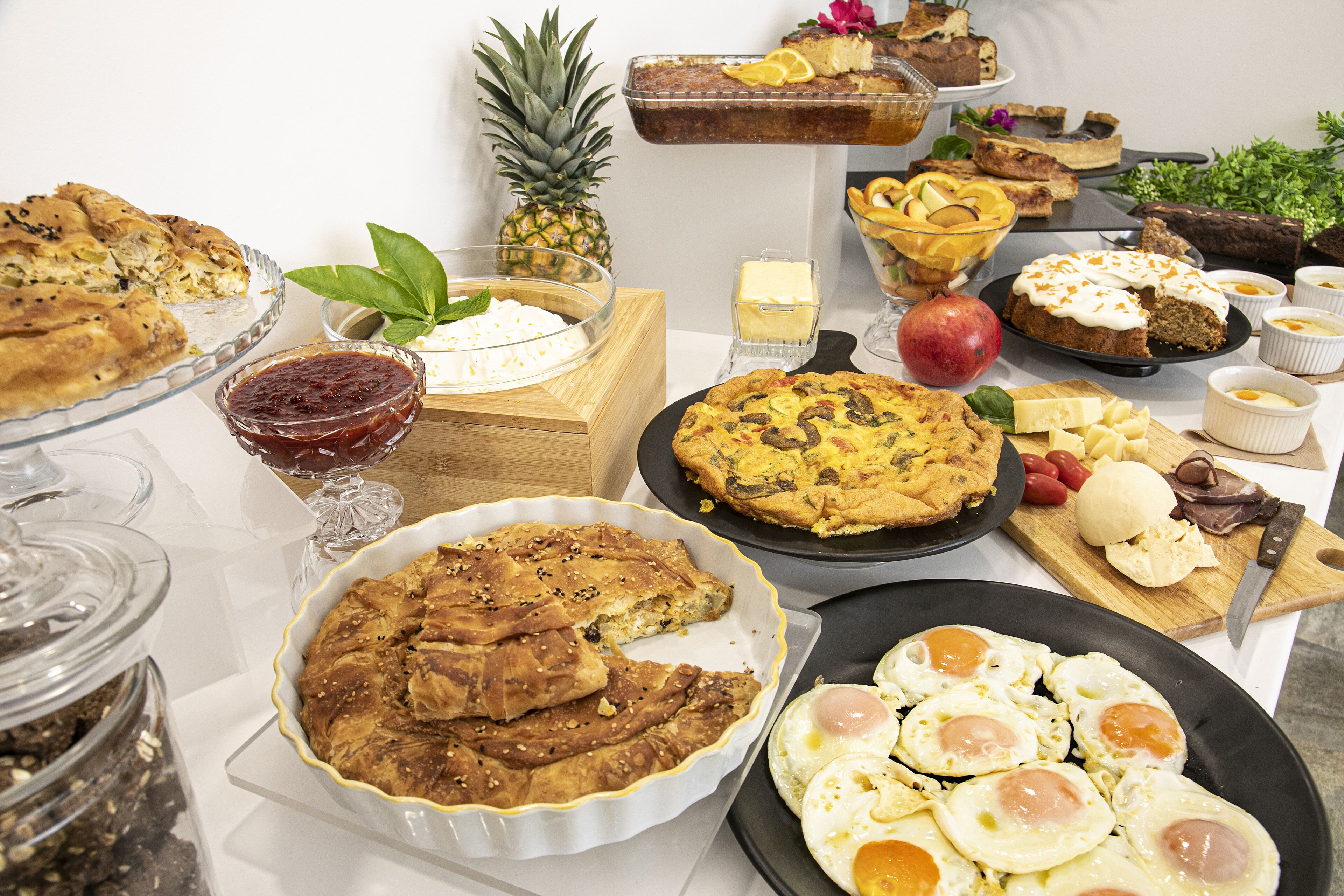 A variety of breakfast foods including pies, eggs, and fruit on a table.