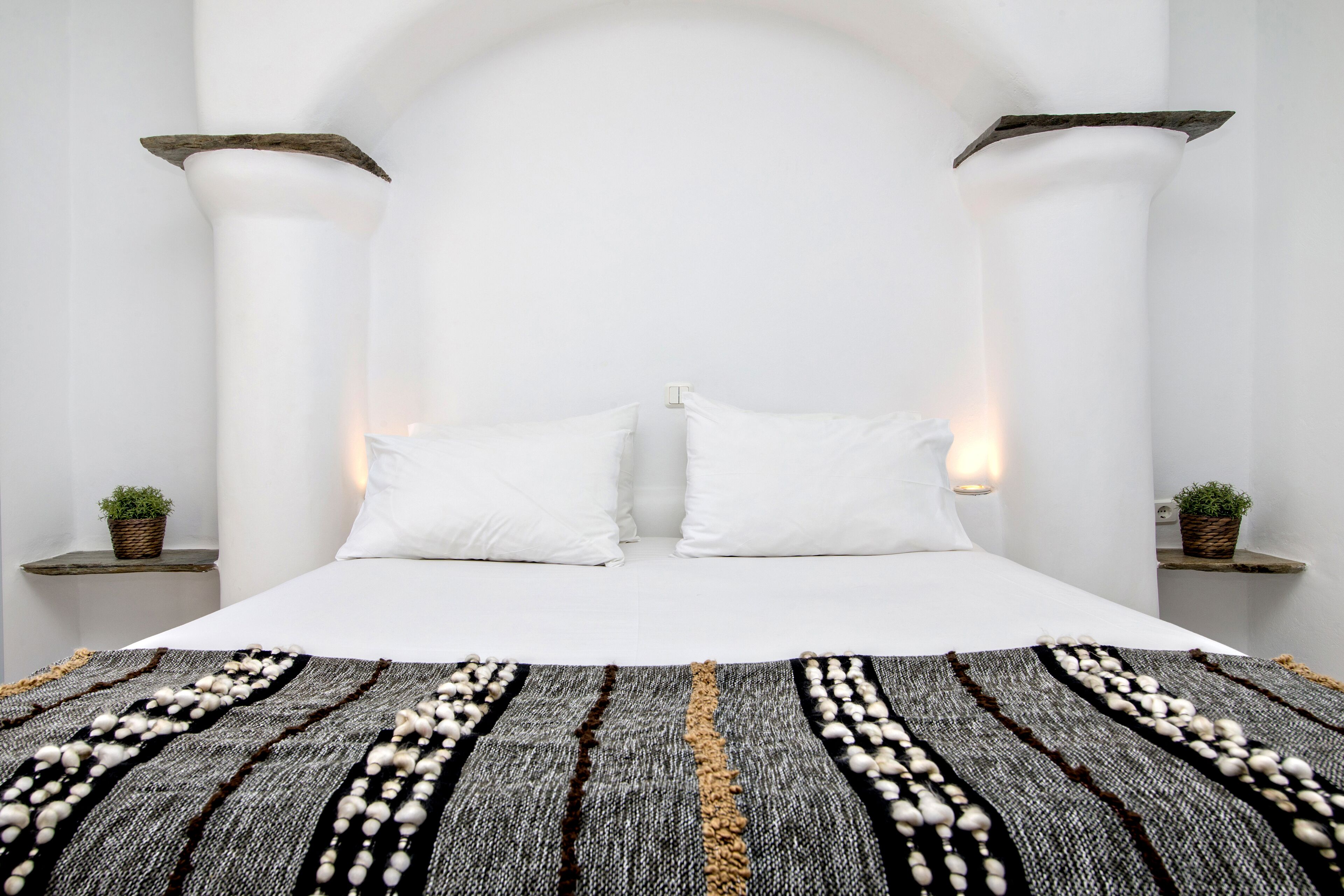 Un dormitorio con una cama grande, almohadas blancas y un tapete decorativo.