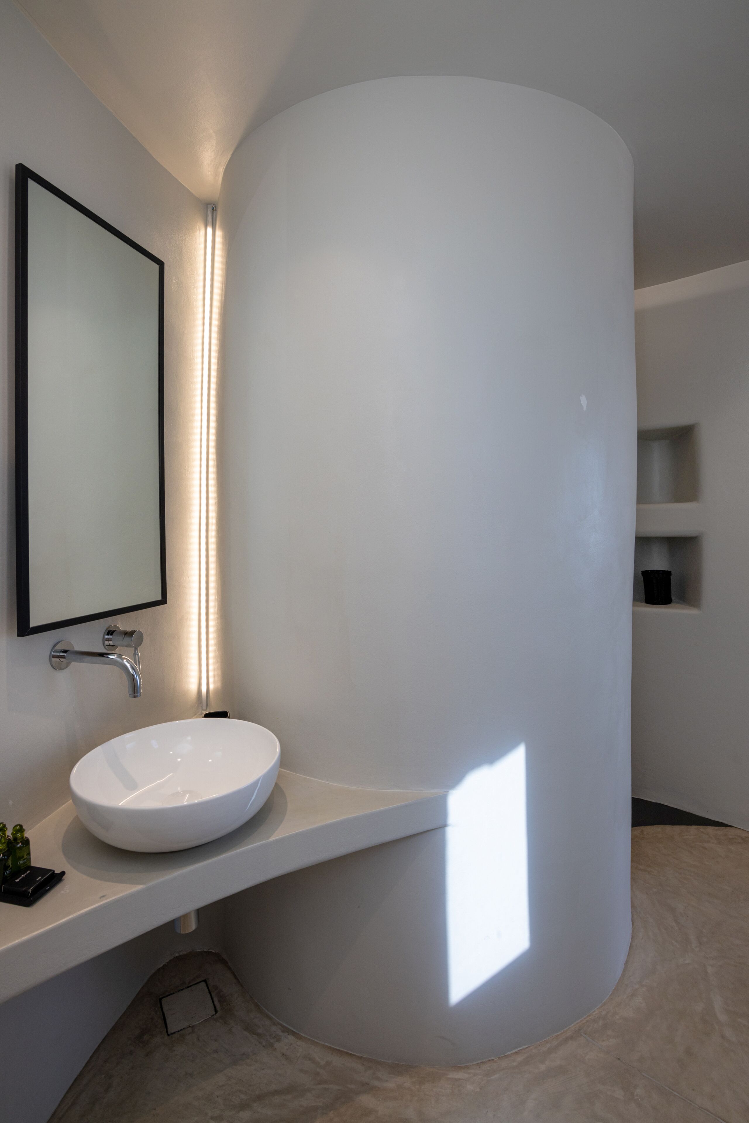 A modern bathroom with a white sink, a mirror, and a light fixture.