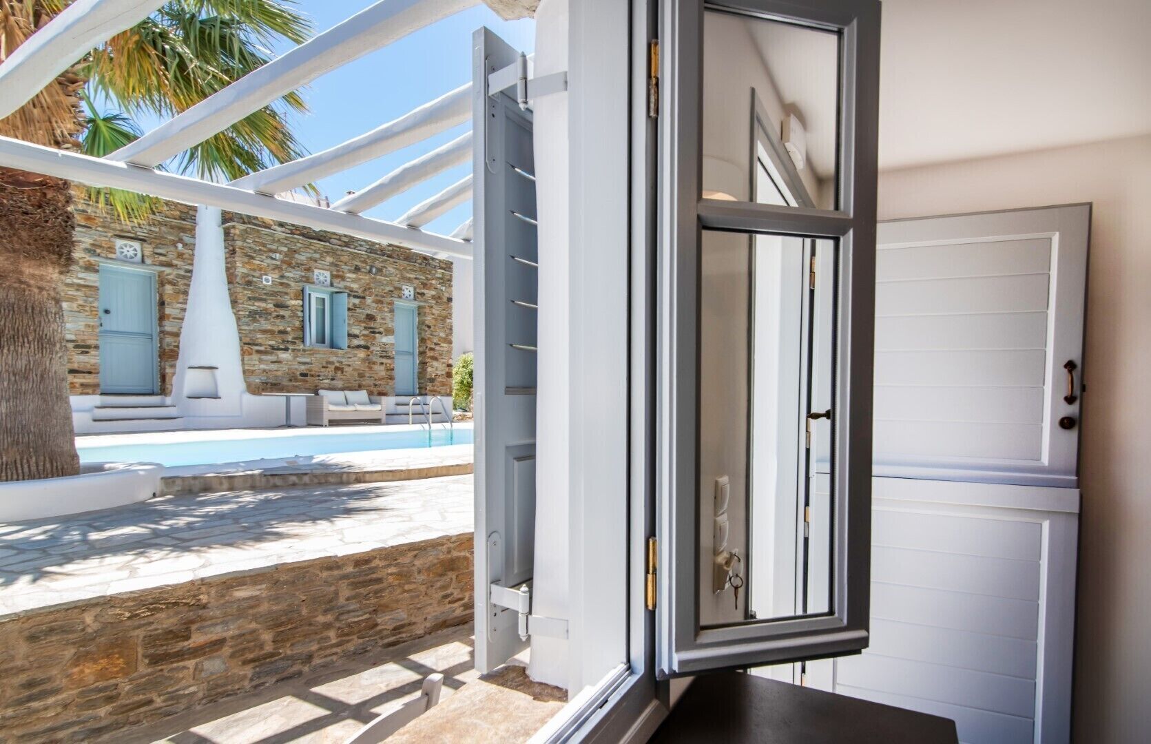 A modern villa with a stone exterior, a pool, and a white door.