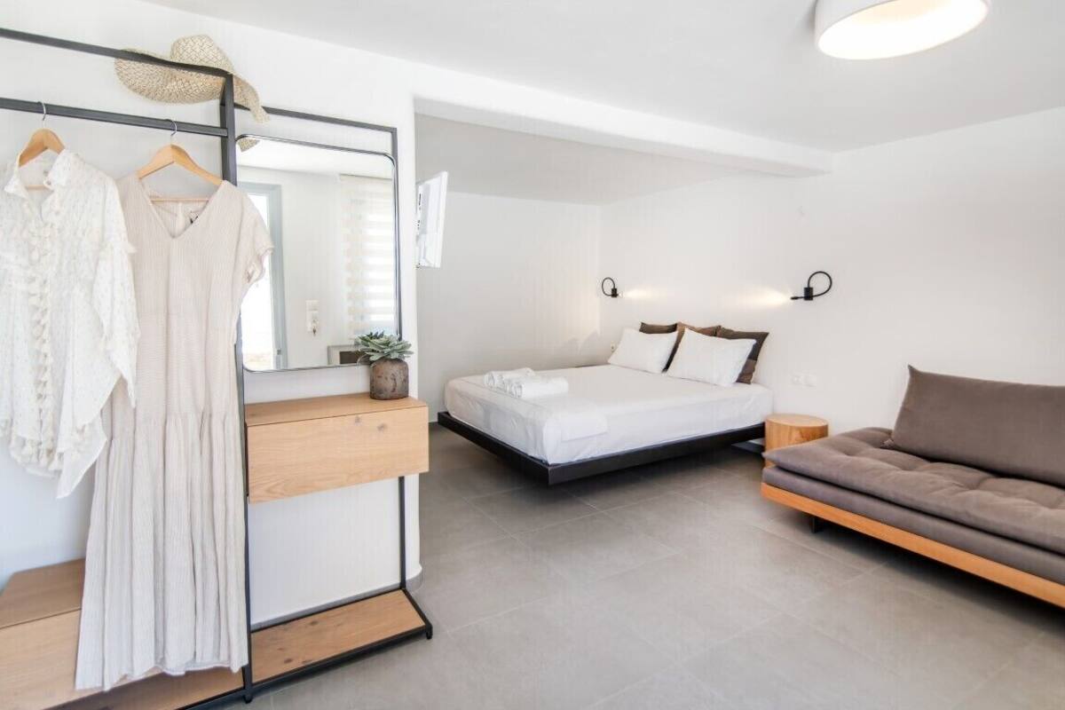 Um quarto moderno com uma cama, um sofá, uma cômoda e um espelho.