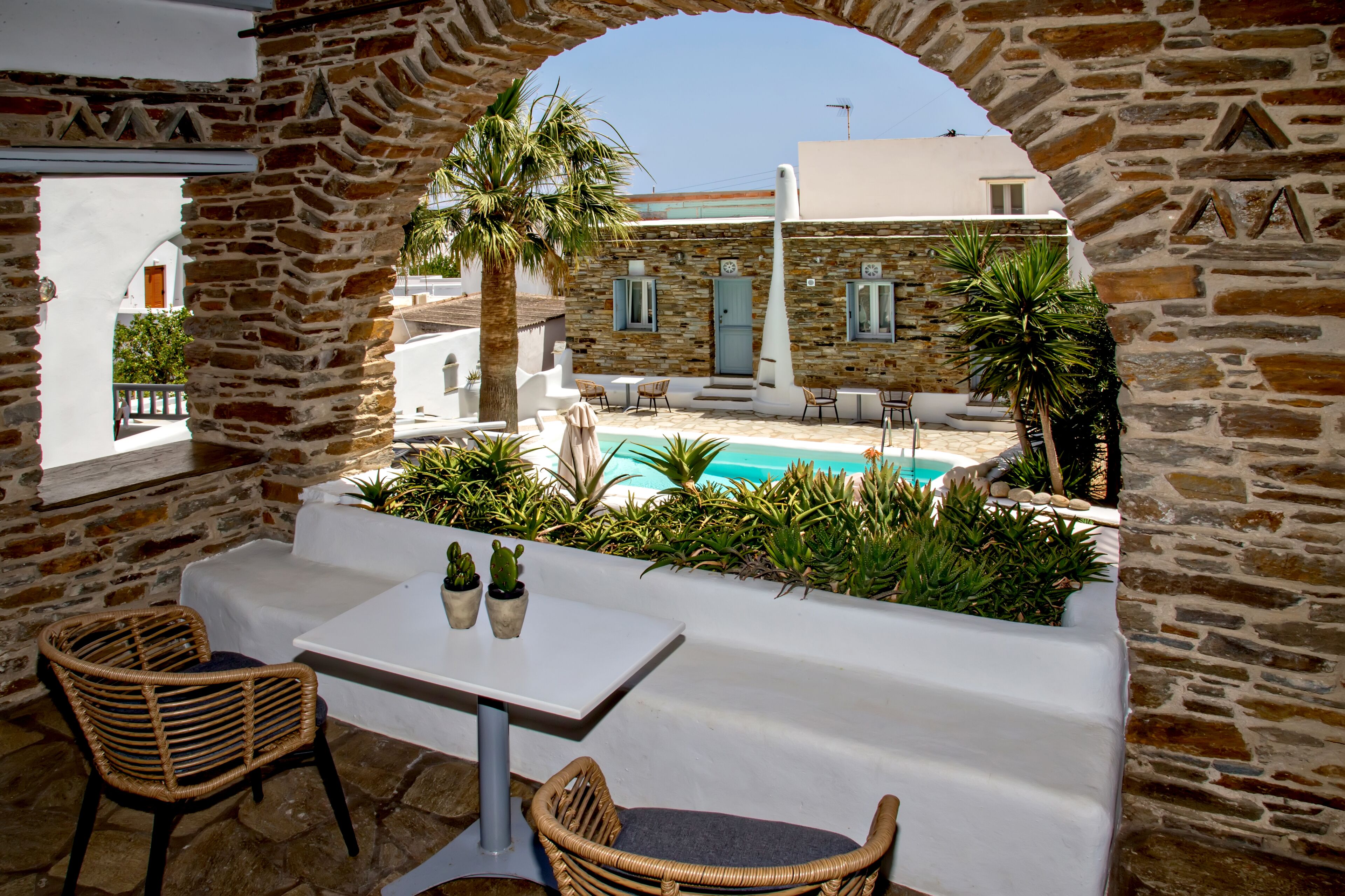 An outdoor seating area with stone walls, a pool, and a view of a building.