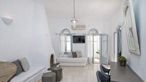 Ein modernes, helles Zimmer mit einem weißen Sofa, einem Esstisch und einem großen Spiegel.