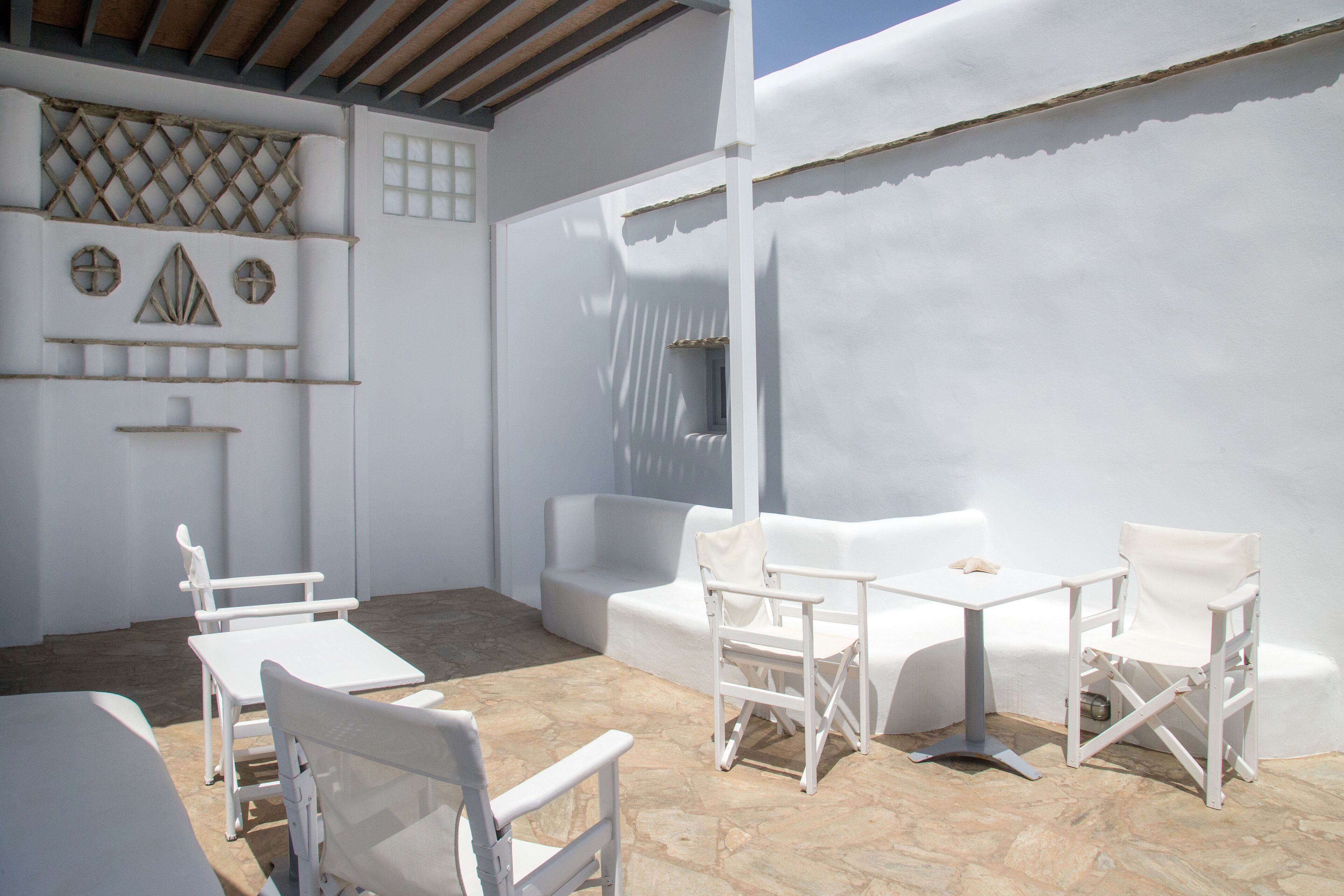 A white outdoor seating area with stone flooring and white furniture.
