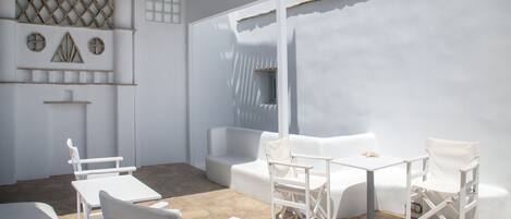 A white outdoor seating area with stone flooring and white furniture.