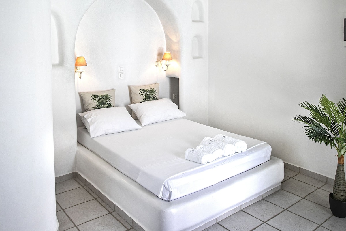 Um quarto moderno com uma cama grande, um candelabro e uma planta em vaso.