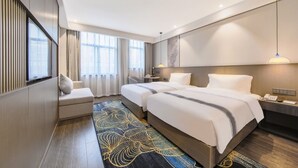 A hotel room with two beds, a seating area, a desk, and a large window.