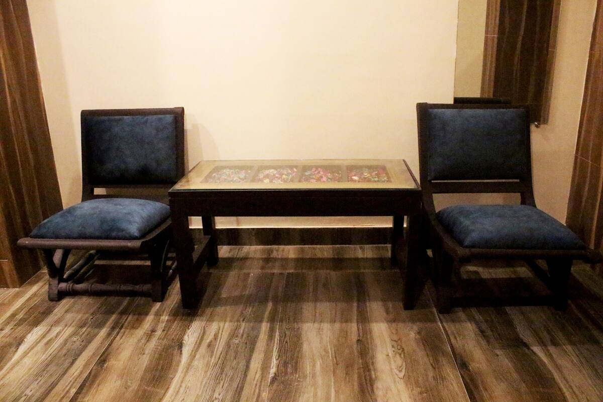 Una habitación con dos sillas de madera y una mesa, ambas con cojines azul oscuro.
