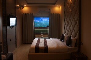 Ein Hotelzimmer mit Bett, Fernseher, Fenster mit Vorhängen und Klimaanlage.