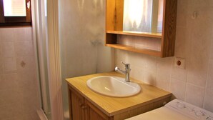 Un baño con tocador de madera, lavamanos blanco y espejo encima.