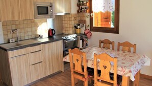 Una cocina compacta con armarios de madera, microondas, estufa y una mesa de comedor con sillas.