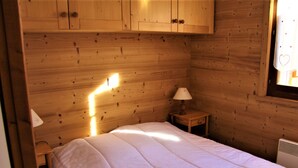 Una habitación de cabaña de madera con una cama, una mesita de noche y una ventana.