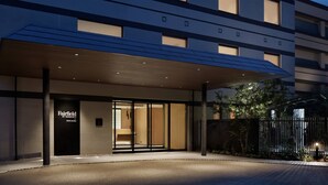 Entrada moderna de hotel con un corredor techado, puertas de cristal grandes y un letrero que dice "Fairfield by Marriott".
