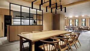 Una cocina moderna con una mesa y sillas de madera, horno empotrado y un ventanal que proporciona luz natural.