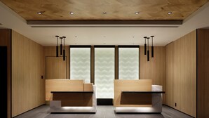 Un área de recepción moderna con paneles de madera, dos mostradores de recepción e iluminación empotrada en el techo.