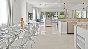 A modern kitchen with a glass dining table, white cabinetry, and a view to the outside. - Style & Luxury: Reunion Villa, Pool, Spa & Cinema (Reunion)