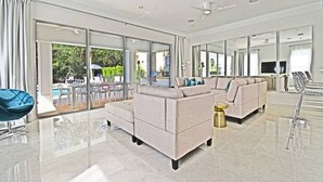 A spacious living room with a large sectional sofa, a coffee table, and a dining area with a glass table. - Style & Luxury: Reunion Villa, Pool, Spa & Cinema (Reunion)