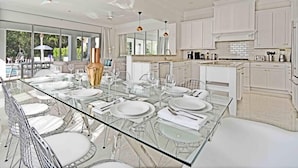 A modern kitchen with white cabinets, a glass dining table, and a view of the outdoors. - Style & Luxury: Reunion Villa, Pool, Spa & Cinema (Reunion)