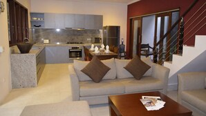 Una sala moderna con sofá, mesa de centro y cocina al fondo.