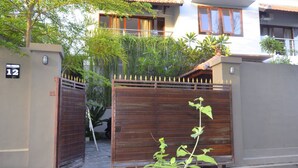 Zona residencial cerrada con un número 12, una puerta de madera y un pequeño jardín con una planta en primer plano.