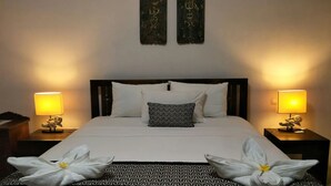 Una cama bien hecha con sábanas blancas, dos almohadas estampadas y lámparas decorativas a cada lado.