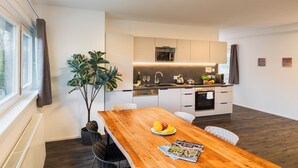 Una cocina moderna con armarios blancos, una mesa de comedor de madera y una planta en maceta.