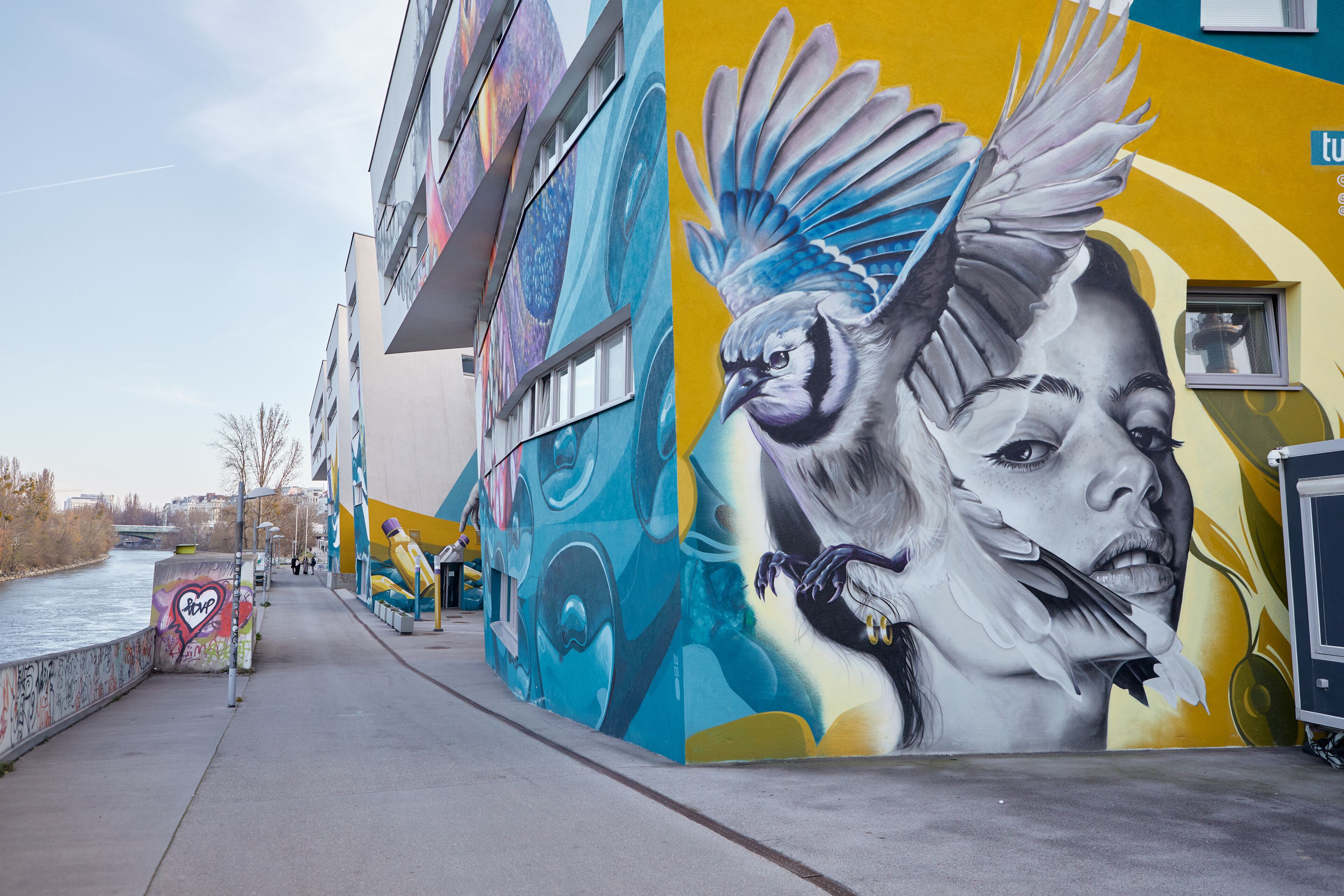 Une fresque ornant le mur extérieur d’un bâtiment, représentant un oiseau et des motifs abstraits.