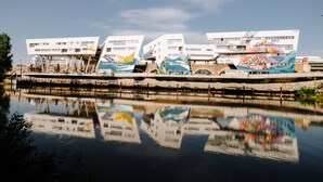 Un edificio moderno con un diseño arquitectónico único, que presenta varias estructuras blancas con murales coloridos en las plantas inferiores.
