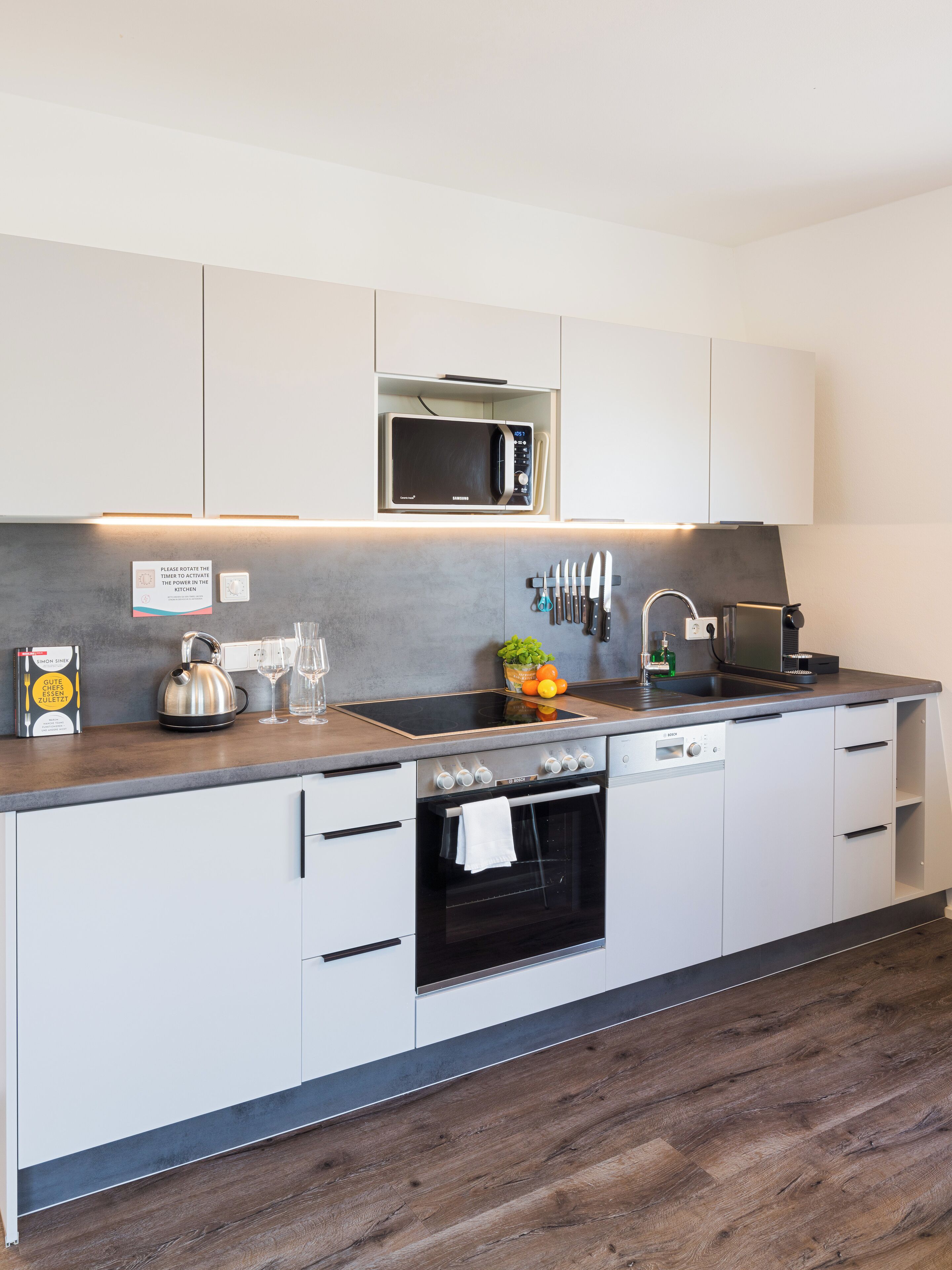 A modern kitchen with white cabinets, a built-in microwave, a sink, and a dishwasher.