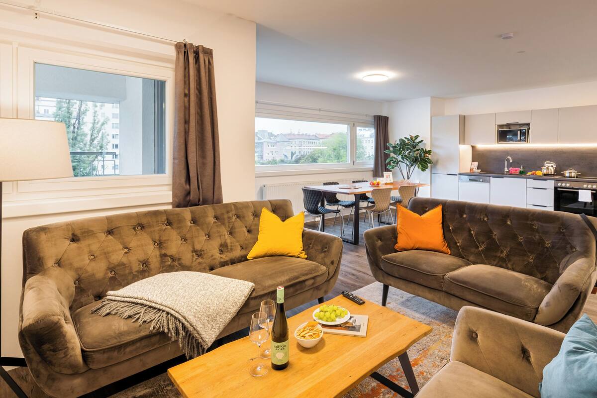 A modern living room with two sofas, a coffee table, and a dining area with a table and chairs.