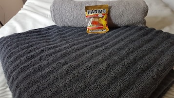 A bed with a grey blanket, a pillow, and a Haribo Goldbären package.