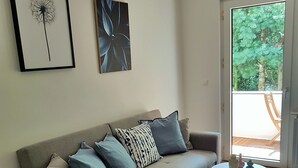 A modern living room with a grey sofa, patterned cushions, a small white table, and a blue rug. - Glück Auf Appartements Walter-Hohmann (Essen)