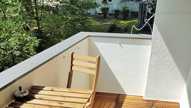 A wooden deck with a table and chairs, surrounded by white walls. - Glück Auf Appartements Walter-Hohmann (Essen)
