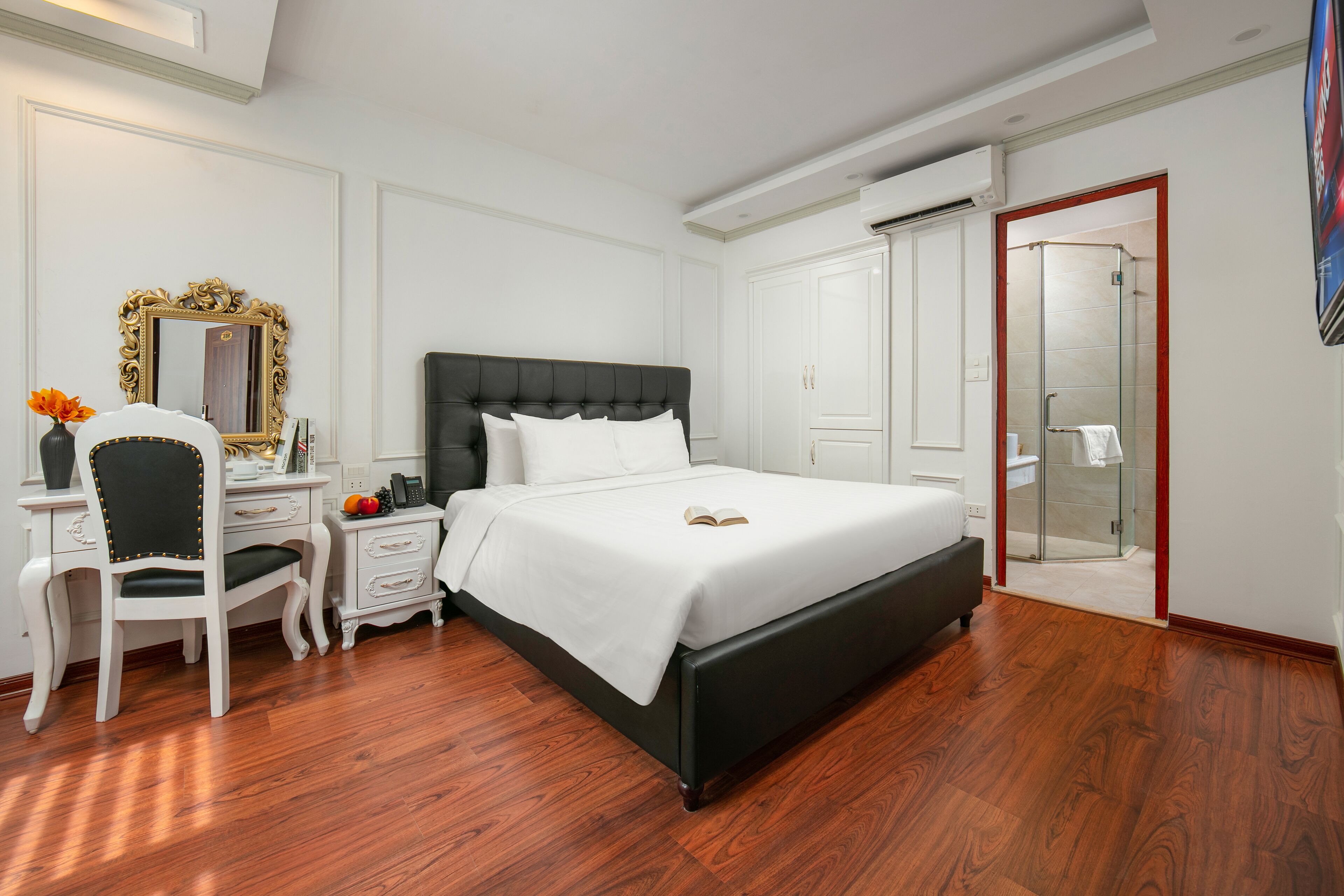 A bedroom with a large bed, a desk with a chair, a mirror, and a walk-in closet.
