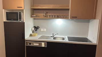 A compact kitchen with a microwave, sink, and dishwasher.