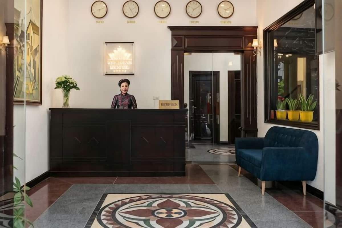A reception desk with a receptionist, a clock, a sofa, and a patterned floor.