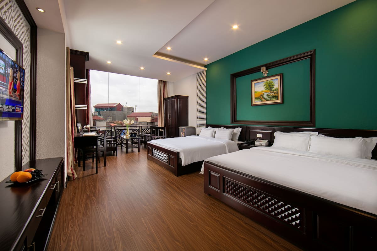 A hotel room with two beds, a dining area, and a TV.