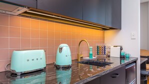 A modern kitchen with two vintage-style toasters, a sink, and a coffee maker. - Downtown Deluxe Heritage with Rooftop Pool overlooking the Viaduct (Auckland)