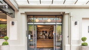 A hotel entrance with a glass door, a staircase leading inside, and two potted plants on either side. - Downtown Deluxe Heritage with Rooftop Pool overlooking the Viaduct (Auckland)