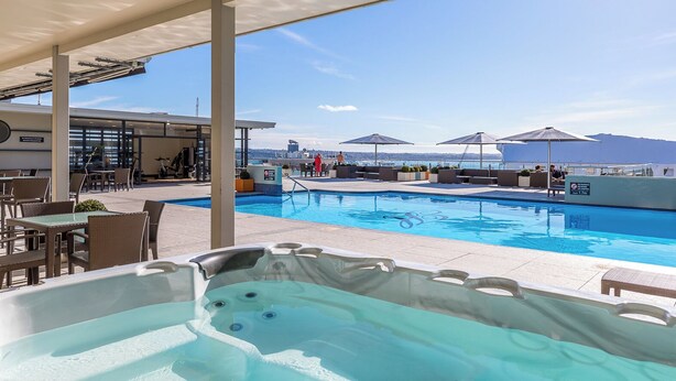 A pool area with a hot tub, outdoor seating, and a view of the city. - Downtown Deluxe Heritage with Rooftop Pool overlooking the Viaduct (Auckland)