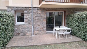 Ein Gebäude aus Stein mit einem Balkon, einer Schiebetür aus Glas und einer Terrasse mit Tisch und Stühlen.