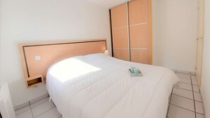 Ein Schlafzimmer mit einem Bett, einem Nachttisch, einer Lampe und einem Kleiderschrank.