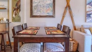 Un coin repas avec une table et des chaises en bois, un luminaire suspendu et des œuvres d’art accrochées aux murs.
