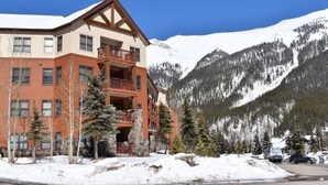 Un hôtel à plusieurs étages, doté d’une façade en pierre, de balcons et surplombant un paysage montagneux.